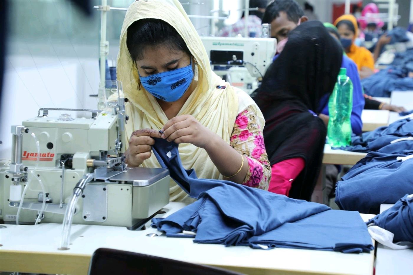 Sewing machine operator assembling a navy knit garment